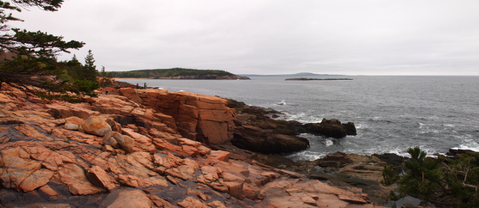 [Two photos stitched together to show the reddish orange, rocky coast on left with ocean on right.]